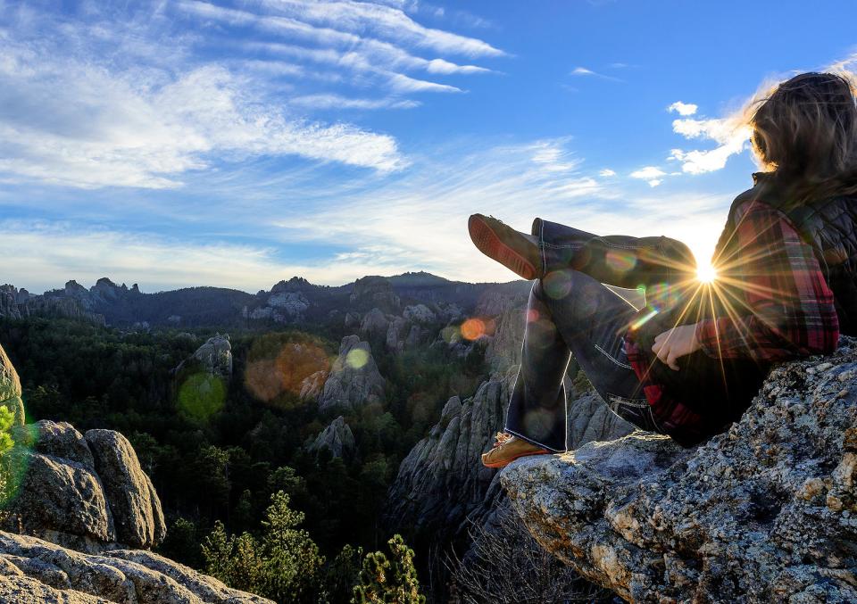 Hiker relaxing on top of peak looking out over vast mountain scenery.